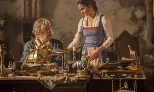 Bella y su padre, Maurice, observan un intrincado molino de viento dorado. La escena evoca la magia de "la bella y la bestia".