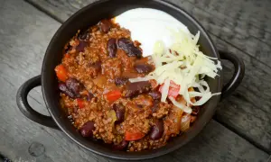 Pyszne chili con carne przepis: sycące danie z mielonym mięsem, fasolą i warzywami, podane z kwaśną śmietaną i startym serem.