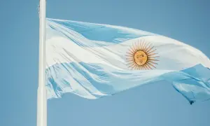 Flaga Argentyny powiewa na wietrze na tle błękitnego nieba.