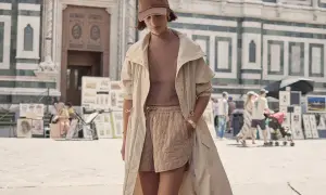 Frau im Athleisure Style mit beiger Jacke und gesteppten Shorts vor einer historischen Fassade.
