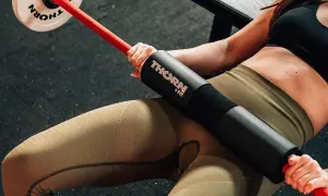 Kobieta wykonuje hip thrust po polsku z gryfem i obciążeniem.