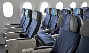Reihe von blauen Flugzeug Sitze mit grauen Kopfstützen und kleinen blauen Kissen.