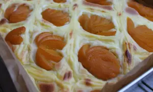 Wilgotne ciasto jogurtowe z budyniem i brzoskwiniami, pieczone w kwadratowej formie.