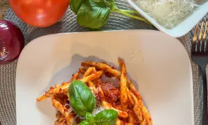 Makaron z sosem nduja, pomidorami, cebulą i bazylią. Pyszne danie, które wyjaśnia, nduja co to jest – pikantna, smarowna włoska kiełbasa.