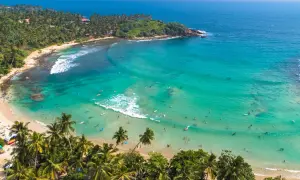 Rajska plaża na Sri Lance z palmami i turkusową wodą, gdzie surferzy cieszą się falami. Sri Lanka ciekawostki: idealne miejsce na relaks i sporty wodne.