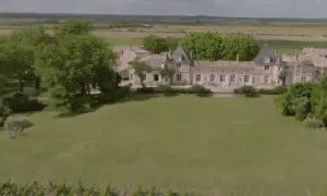 Un magnifique château bordelais, typique de la route des châteaux du Médoc, se dresse au milieu de vignes et d'arbres verdoyants.