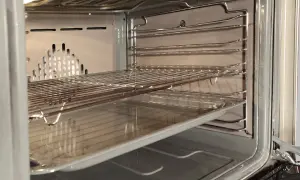 Wnętrze piekarnika z rusztami i blachą, gotowe do czyszczenia katalitycznego.