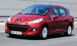 Czerwony Peugeot 207 1.6 HDi w ruchu, z widocznym logo marki i tablicą rejestracyjną.