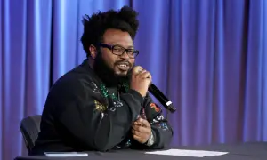 James Fauntleroy, a songwriter and producer, speaks into a microphone. His extensive James Fauntleroy discography is a testament to his talent.