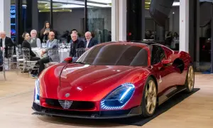 Lśniący, czerwony Alfa Romeo 33 z złotymi felgami prezentuje się na tle sali bankietowej, gdzie goście przyglądają się mu z zaciekawieniem.
