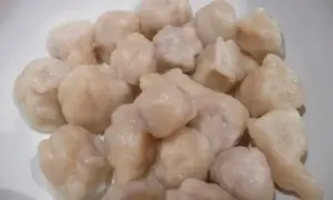 Gęsto ułożone, jasne kołduny w rosole, gotowe do podania.