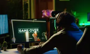 Gracz sfrustrowany przegraną, ekran "GAME OVER". Może to znak, że czas pomyśleć, jak zmniejszyć ping i poprawić swoje wyniki w grach online.