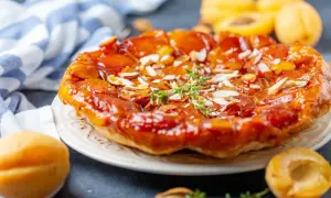 Tarte aux abricots caramélisée, garnie d'amandes effilées et d'une touche de thym frais. Un délice doré et gourmand.