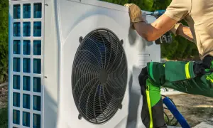 Technik w rękawiczkach dokręca śrubę przy pompie ciepła. Proces odpowietrzania pompy ciepła wymaga precyzji.