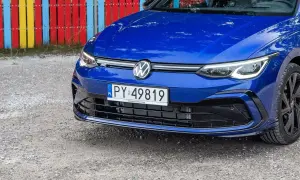Niebieski Volkswagen z tablicą rejestracyjną PY 49819 na tle kolorowego płotu.