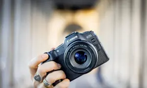 Mano che tiene una fotocamera Canon EOS R8 con obiettivo 50mm f/1.8 STM. Un modello compatto, ideale per chi cerca la qualità di un sensore canon apsc.