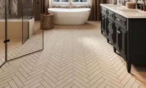 Elegant bathroom with a freestanding tub, double vanity, and glass shower, all set on beautiful natural stone flooring laid in a herringbone pattern.