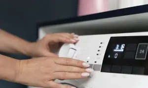 Ręce ustawiają program na pralce Bosch, która wyświetla błąd E36.