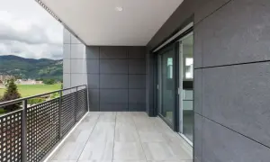 Nowoczesny balkon z jasnymi płytkami na podłodze i ciemnymi panelami na ścianie. To właśnie gres, trwały i estetyczny materiał, idealny na zewnątrz.