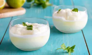 Due bicchieri di sorbetto al limone, guarniti con menta fresca, su un tavolo di legno blu.