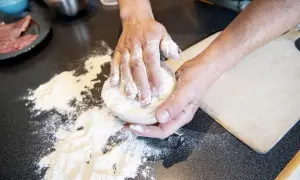 Händer som knådar deg med mjöl för en äkta neapel pizza.