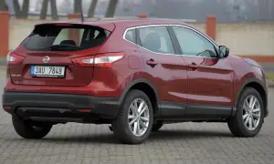 Czerwony Nissan Qashqai 2015 z czeskimi tablicami rejestracyjnymi stoi na brukowanym placu.