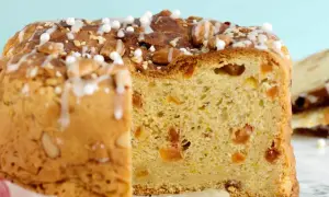 En skiva av ett gyllene panettone, dekorerad med mandlar och glasyr. Detta är ett recept på original panettone.