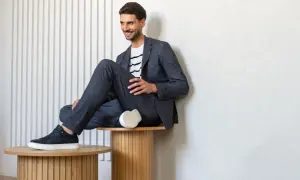 Uśmiechnięty mężczyzna w granatowym garniturze i pasiastym T-shircie, prezentujący styl smart casual.