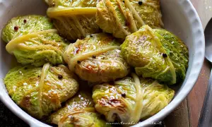 Involtini di verza con carne, cotti in teglia, conditi con olio e pepe nero.