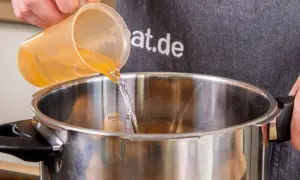Flüssigkeit wird in einen Schnellkochtopf gegossen, bereit für die Zubereitung von Kartoffeln.