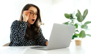 Zaskoczona kobieta w okularach patrzy na laptopa. Czyżby właśnie dowiedziała się, że od kiedy 35 dni urlopu?