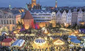 Tłumy ludzi na jarmarku świątecznym w Gdańsku. Widać karuzelę, stragany z ozdobami i iluminacje.