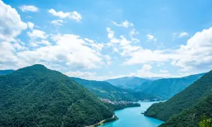 Malownicze jezioro otoczone zielonymi wzgórzami, typowe dla krajobrazów Bałkanów, gdzie państwa takie jak Czarnogóra zachwycają naturą.