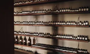 Wiele buteleczek z perfumami na drewnianych półkach. Idealne miejsce, gdzie trzymać perfumy, by były zawsze pod ręką.