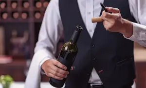 Un sommelier mostra come usare cavatappi per aprire una bottiglia di vino.