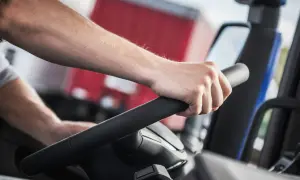 Main d'un conducteur sur le volant d'un camion. La question "carte fimo c'est quoi" pourrait être posée par quelqu'un qui apprend ce métier.