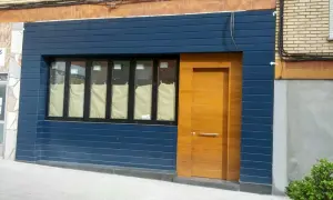 Fachadas de locales convertidos en viviendas, con puerta de madera y ventanas cubiertas.
