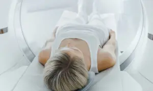 Kobieta leży na stole do rezonansu magnetycznego, przygotowując się do badania tk klatki piersiowej.