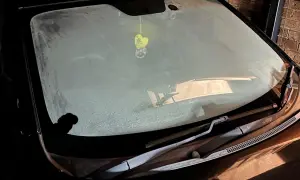 En frostig vindruta på en bil. En gul hjärtformad doftgran hänger från backspegeln.