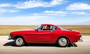Irv Gordon kör sin röda Volvo P1800 över ett öppet fält under en klarblå himmel.