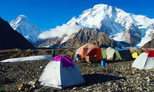 Namiot obok szerokiego szczytu K2, obóz pod górą, zimowy krajobraz, błękitne niebo.