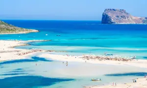 Rajska plaża z turkusową wodą i skalistą wysepką w oddali. Czy to Rodos czy Kreta? Trudno odróżnić ten cud natury.