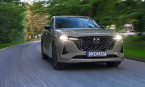 Nowa Mazda CX-60 3.3 diesel sunie po krętej drodze wśród zieleni.