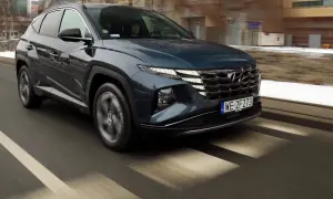 Ciemnogranatowy Hyundai Tucson jedzie po ulicy, widać jego przednią część i grill.