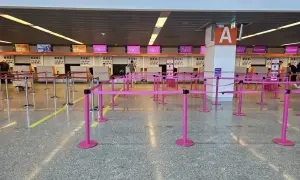 Puste stanowiska odprawy na lotnisku, z różowymi barierkami i tablicami Wizz Air.
