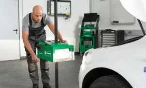 Un mécanicien ajuste un appareil de mesure pour vérifier l'alignement des phares d'une voiture. Cet outil est essentiel pour savoir a quoi sert un phare : éclairer la route en toute sécurité.
