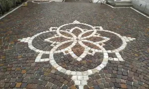 Vicolo carrabile in porfido con un elegante motivo floreale centrale.