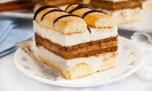 Kawałek ciasta z biszkoptem, kremem mascarpone i karmelem, ozdobiony czekoladą.