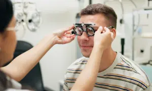 Okulista dopasowuje soczewki próbne mężczyźnie. Idealny moment, by skorzystać z promocji na okulary i zadbać o wzrok.