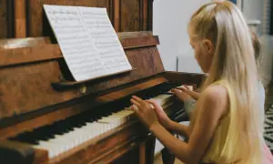 Dzieci grają na keyboardzie, patrząc na nuty literowe.